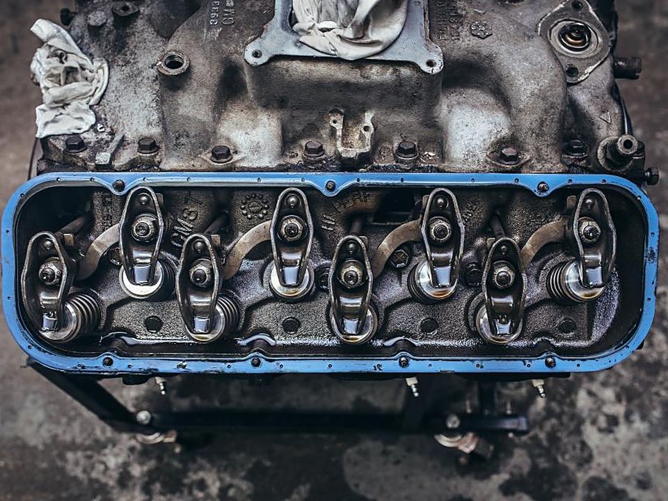 An engine block on a workshop floor with the valve cover off