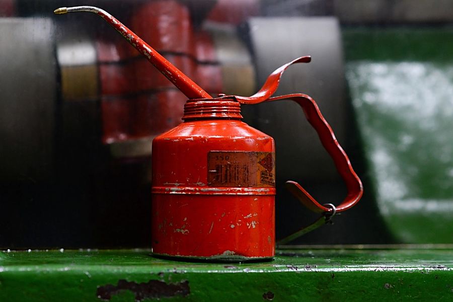 A red oil can on a workbench